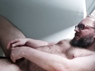 Chastity locked bear plays with his balls