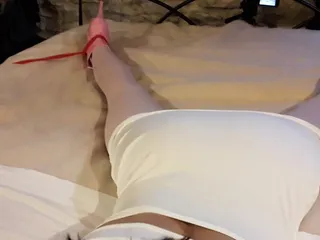 Laura is wearing a sexy white dress, pink pantyhose and platform heels, tied up and gagged in a bed